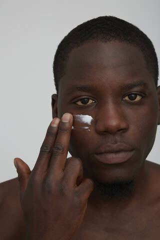 Portrait of African man applying face cream stock photo