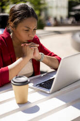 Businesswoman working on laptop outdoors, London, UK - MAUF02952