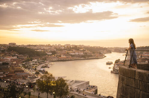 Frau betrachtet Panoramablick auf Porto bei Sonnenuntergang, Portugal - AHSF00863