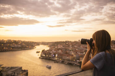 Frau, die ein Foto von Porto bei Sonnenuntergang macht, Portugal - AHSF00866