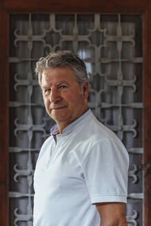 Portrait of a senior man in front of an iron door - MOSF00017