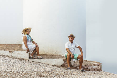 Älteres Touristenpaar auf einer Treppe in einem Dorf sitzend, El Roc de Sant Gaieta, Spanien - MOSF00021