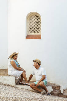 Glückliches älteres Touristenpaar, das auf einer Treppe in einem Dorf sitzt, El Roc de Sant Gaieta, Spanien - MOSF00022