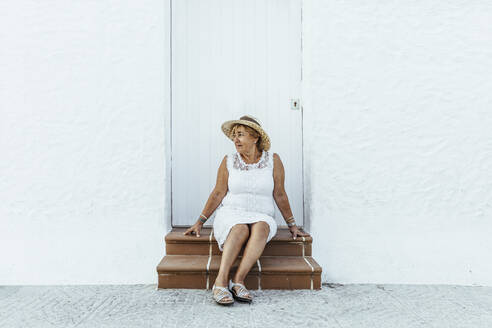 Senior tourist sitting on stoop in a village, El Roc de Sant Gaieta, Spain - MOSF00024