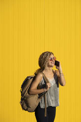 Young woman on the phone in front of yellow background - DAMF00145