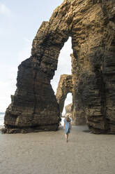 Frau, die am Strand von Cathedrals mit Felsen spazieren geht, Rückansicht, Galicien, Spanien - AHSF00897