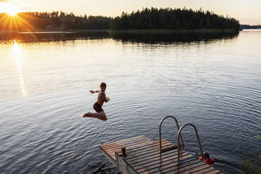 Boy jumping into lake - JOHF02656