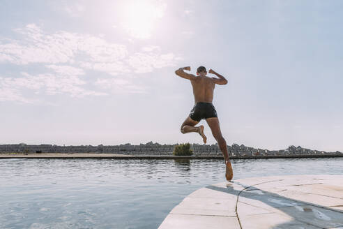 Young man jumping into water from a pier - MOSF00048