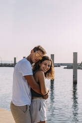Glückliches junges Paar, das sich am Meer umarmt - MOSF00054