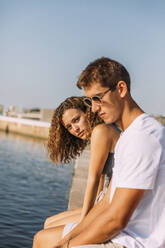 Junges Paar sitzt auf einem Pier am Meer - MOSF00059