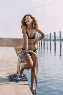 Happy attractive young woman on a pier at the sea - MOSF00081