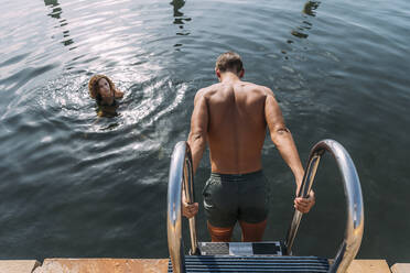 Young man getting into the water from jetty - MOSF00084