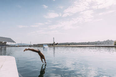 Young man jumping into water from a pier - MOSF00089