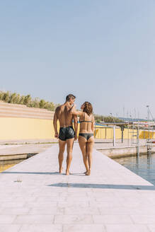 Young couple walking on a pier at the sea - MOSF00090