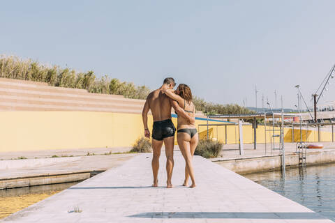 Junges Paar spaziert auf einer Seebrücke am Meer, lizenzfreies Stockfoto