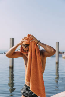 Young mna drying his hair with a towel at the sea - MOSF00093