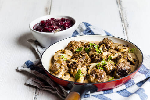 Bratpfanne mit schwedischen Kottbullar-Fleischbällchen in Pilzsoße und Schüssel mit pürierten Preiselbeeren - SBDF04056