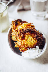 Bowl of crunchy Jewish latkes with sour cream - SBDF04060