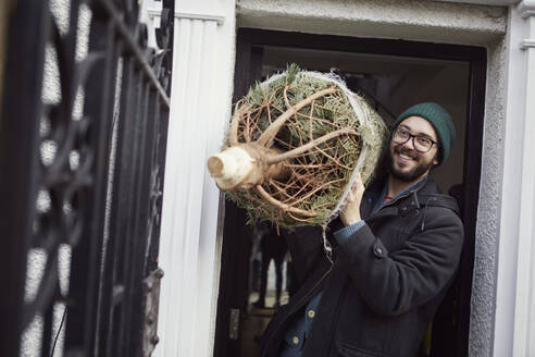 Lächelnder Mann mit Weihnachtsbaum - JOHF02734