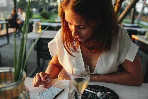 Frau im Restaurant, die ein Mobiltelefon benutzt - JOHF02754