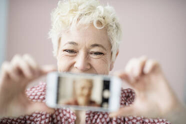 Woman holding cell phone with her photo - JOHF02787