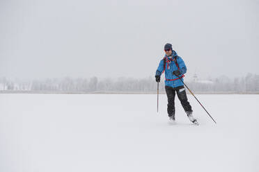 Mann beim Schlittschuhlaufen auf zugefrorenem See - JOHF03026