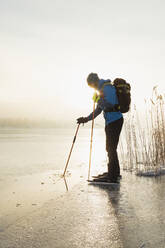 Mann beim Schlittschuhlaufen auf zugefrorenem See - JOHF03030