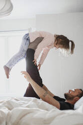 Father playing with daughter in bed - JOHF03247