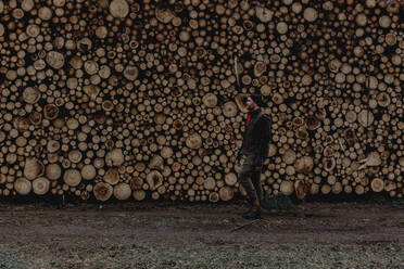 Man standing in front of stack of logs - JOHF03260