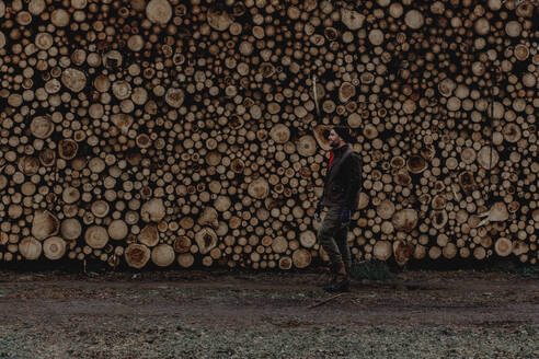 Mann steht vor einem Stapel Holzscheite - JOHF03260