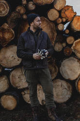 Man standing in front of stack of logs - JOHF03265