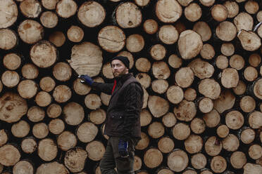 Man standing in front of stack of logs - JOHF03271