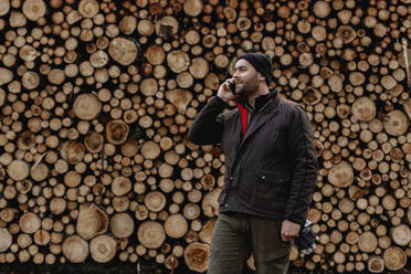 Man standing in front of stack of logs - JOHF03272