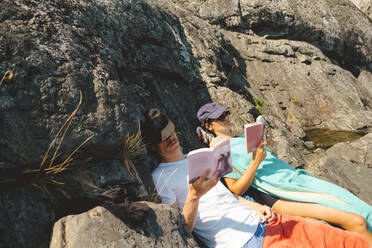 Mann und Frau lesen Bücher auf Felsen - JOHF03303