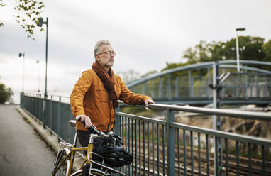 Man with bicycle standing on bridge - JOHF03435