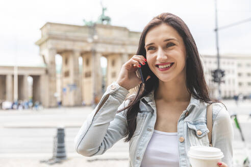 Glückliche junge Frau am Telefon am Brandenburger Tor, Berlin, Deutschland - WPEF02041