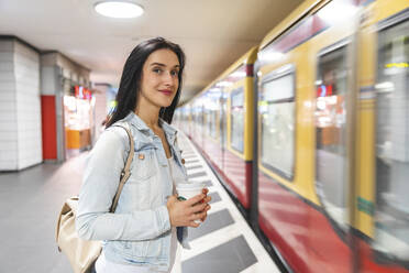 Junge Frau an einer U-Bahn-Station, die auf den Zug wartet, Berlin, Deutschland - WPEF02043