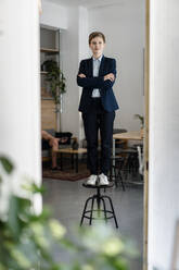 Portrait of a confident businesswoman standing on a stool - KNSF06736