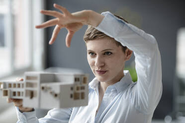Confident businesswoman holding architectural model in office - KNSF06742