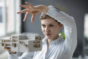 Selbstbewusste Geschäftsfrau mit Architekturmodell im Büro - KNSF06742