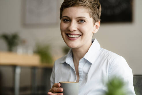 Porträt einer glücklichen Geschäftsfrau, die eine Tasse Kaffee hält - KNSF06746