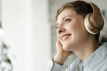Porträt einer glücklichen Geschäftsfrau, die mit Kopfhörern Musik hört - KNSF06749