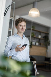 Businesswoman with cell phone and skateboard in a cafe - KNSF06779