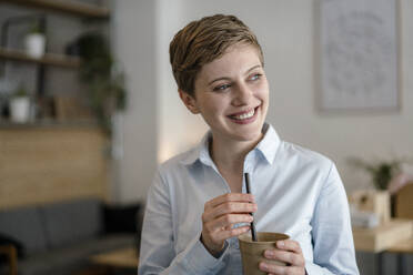 Happy businesswoman in a cafe holding a mug - KNSF06783