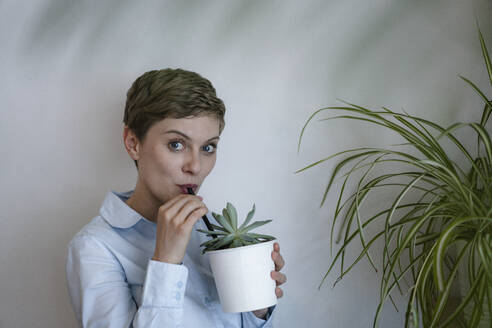 Porträt einer Geschäftsfrau, die aus einer Topfpflanze trinkt - KNSF06784
