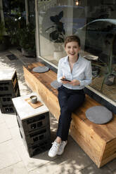 Portrait of a happy businesswoman at a cafe - KNSF06789