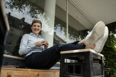 Portrait of a happy businesswoman relaxing at a cafe - KNSF06790