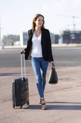 Lächelnde Geschäftsfrau mit Gepäck auf dem Weg - GIOF07194