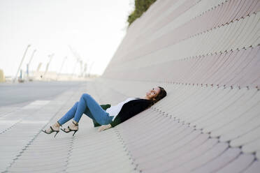 Businesswoman relaxing outdoors lying on slabs - GIOF07199