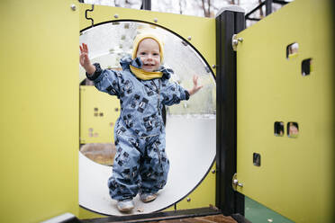 Porträt eines glücklichen Kleinkindes auf einem Spielplatz im Winter - EYAF00561